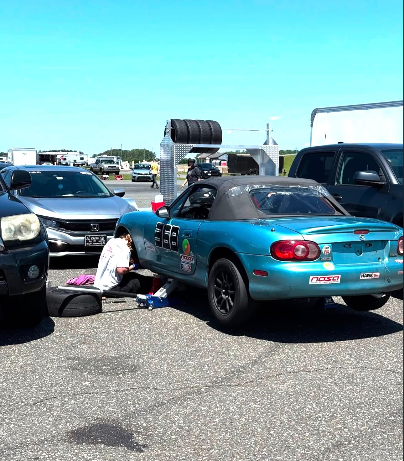 Taylor working hands-on under her race car at an event